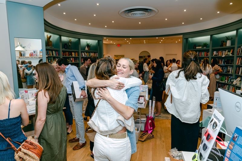 Guests hugging and mingling at the Moxies product launch in Greenwich, Connecticut.